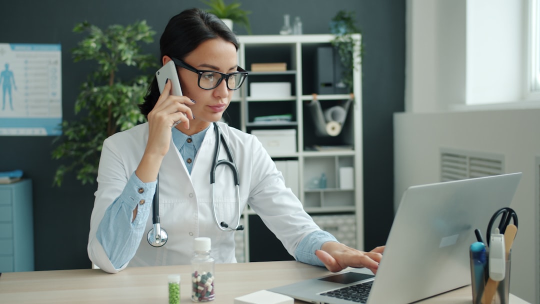 Doctor coordinating care by phone while working at a laptop